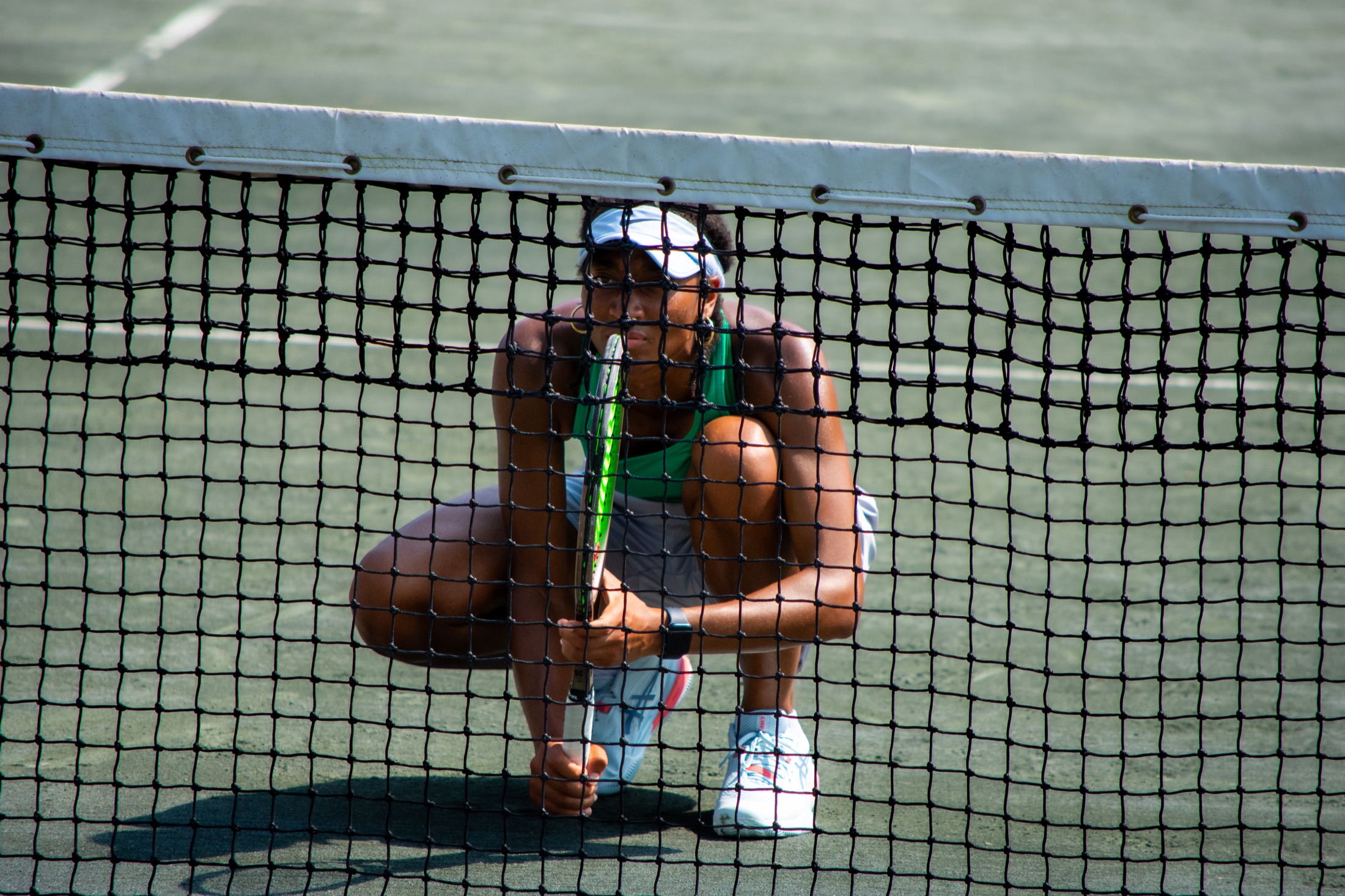 Tennis player crouching behind the net during a break in play